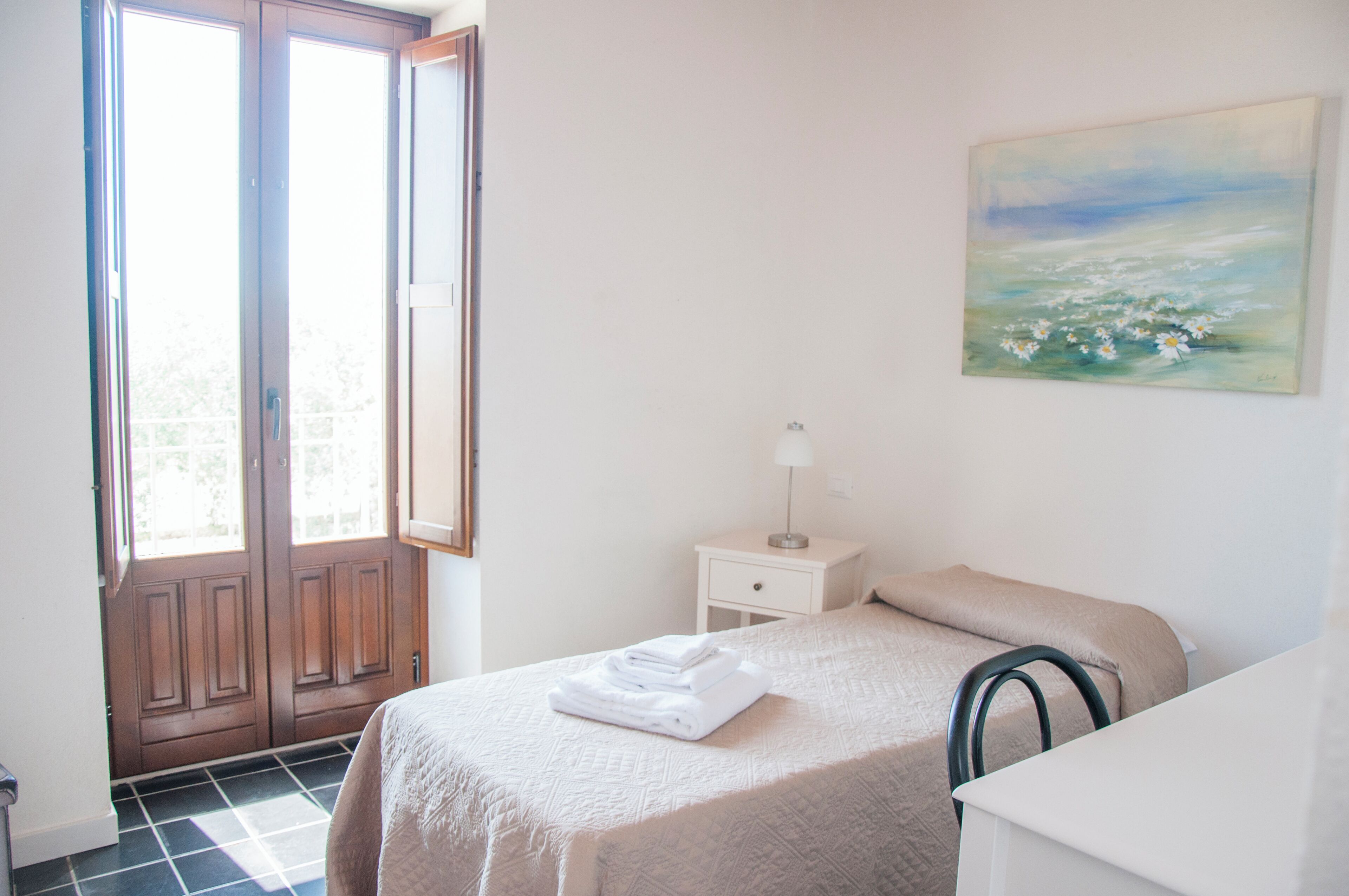 Camera da letto con un letto, un comodino, una lampada, un quadro e una porta con vista.
