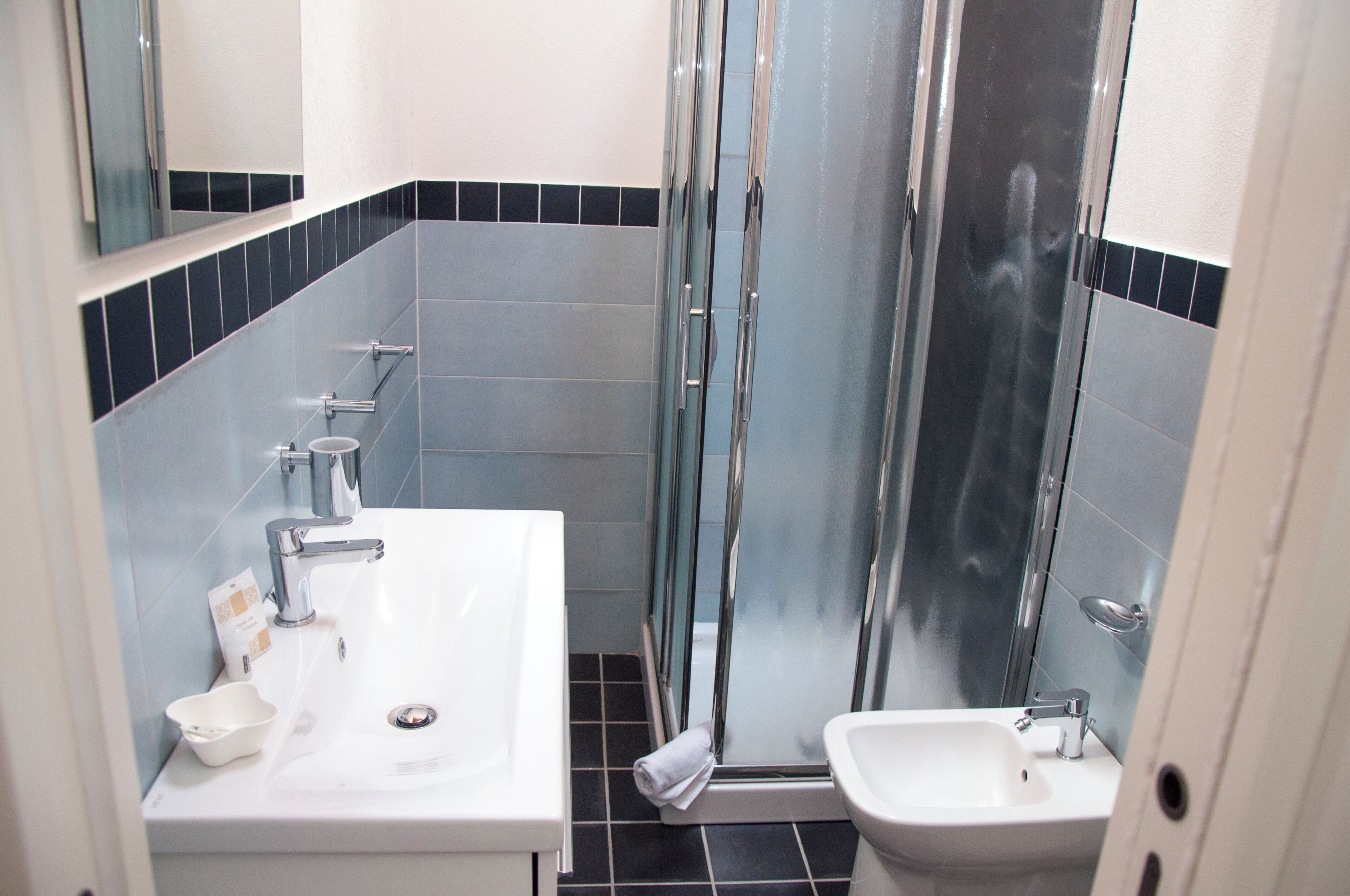 Un baño con lavamanos blanco, un espejo y una cabina de ducha de vidrio.
