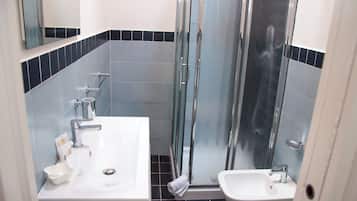 Un baño con lavamanos blanco, un espejo y una cabina de ducha de vidrio.