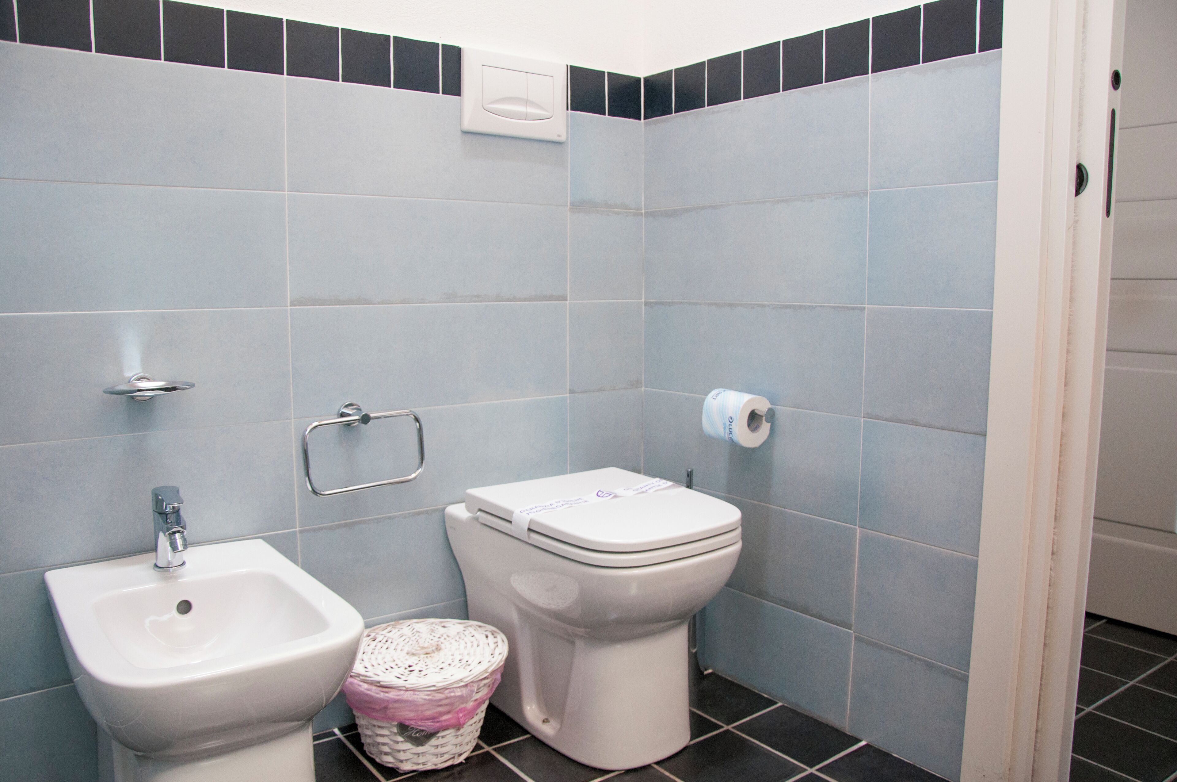 A bathroom with a bidet, toilet, and a hand dryer.
