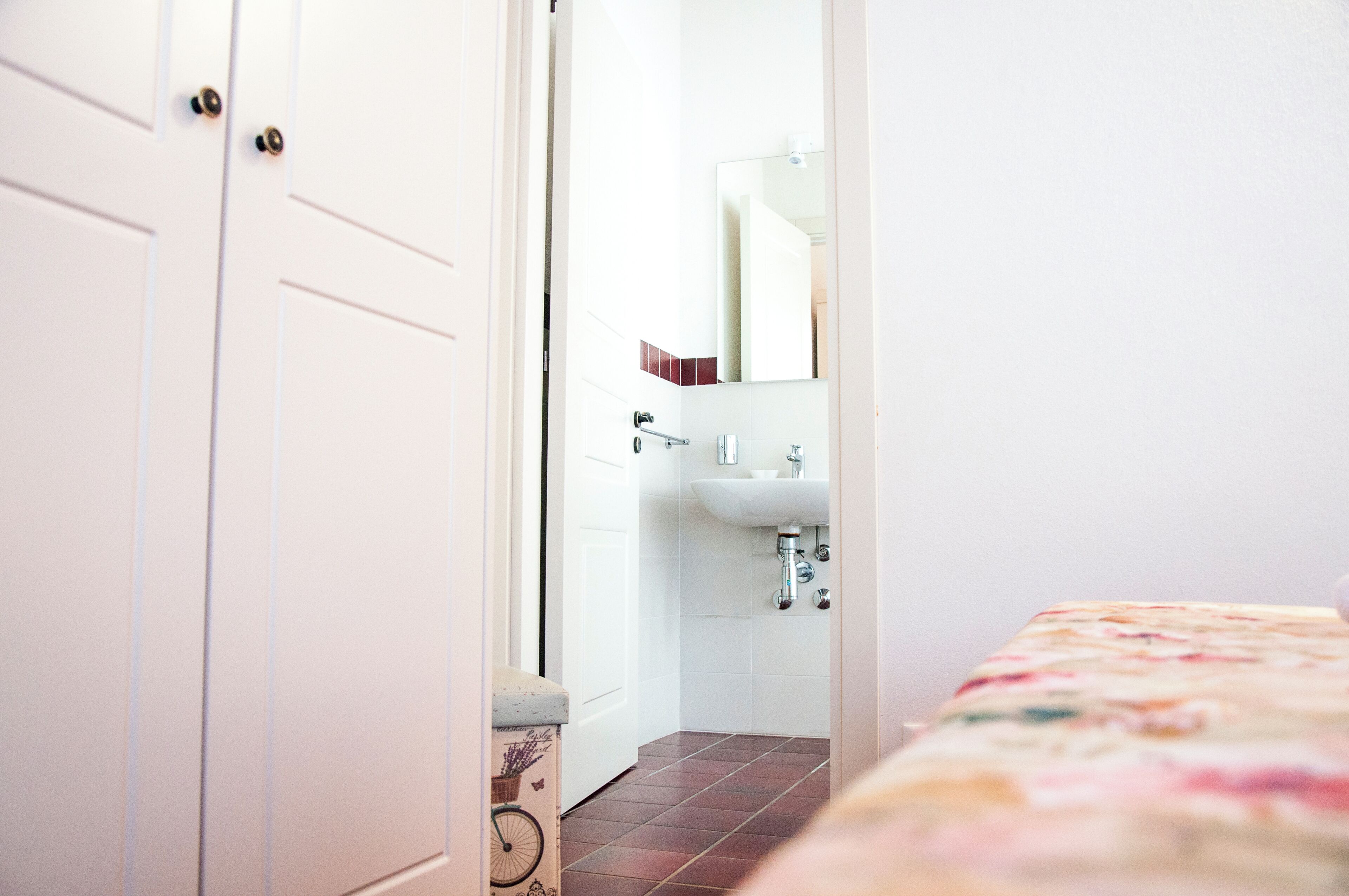 A narrow hallway leading to a bathroom with a white sink and a mirror.