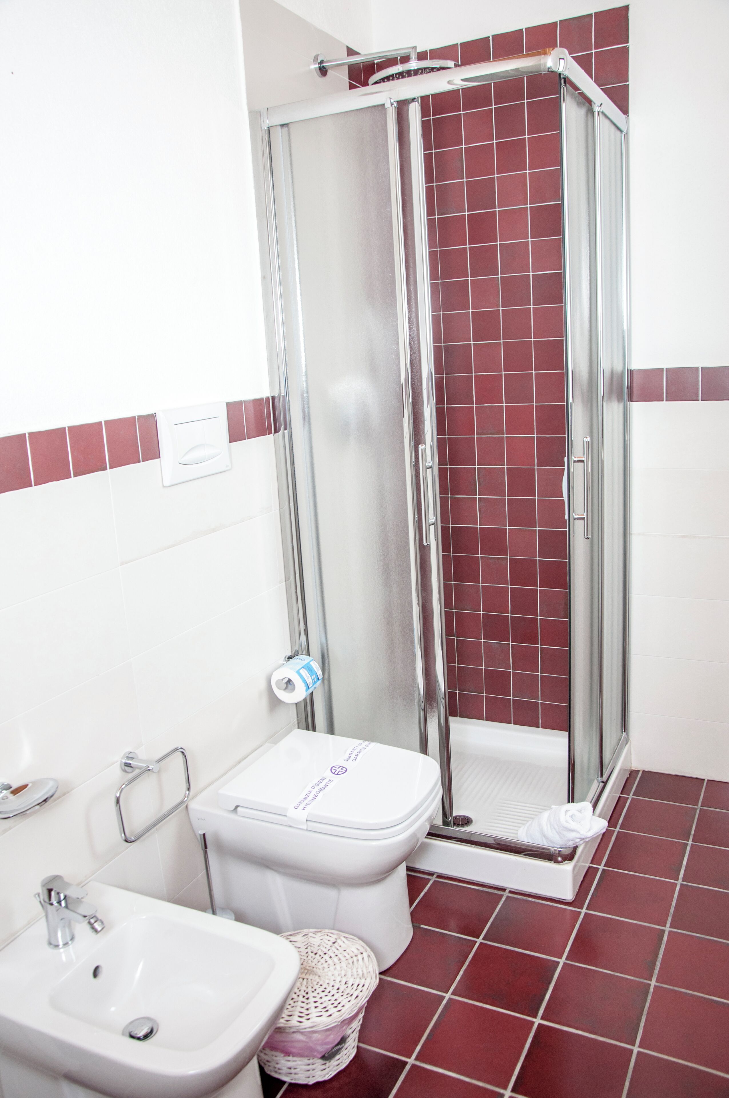 A bathroom with a shower, toilet, sink, and a tiled floor.
