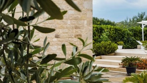 Una pared de piedra, una planta en maceta y una zona de estar exterior blanca con escalones.