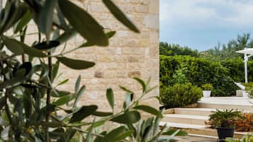 A stone wall, a potted plant, and a white outdoor seating area with steps.