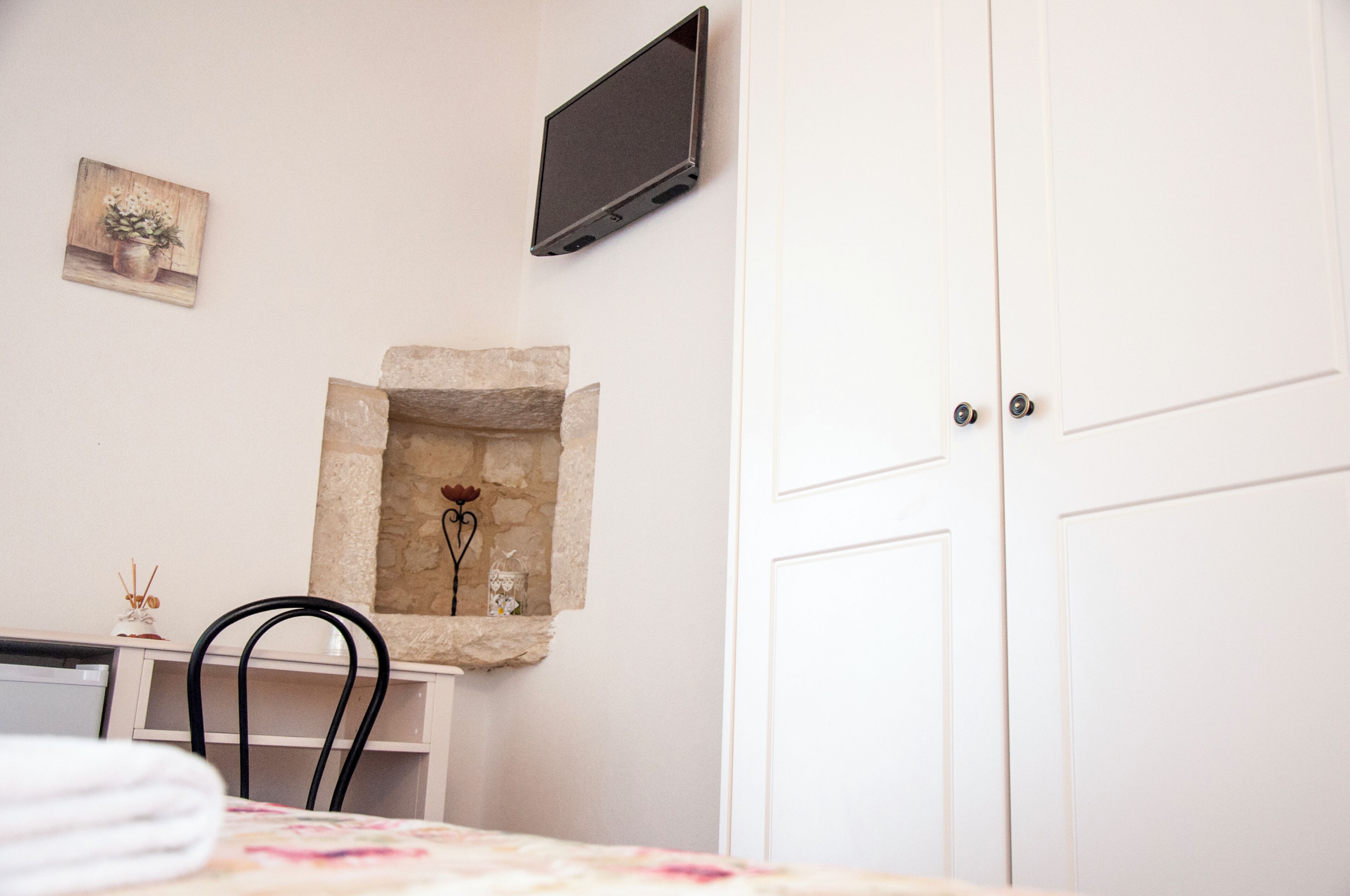 Una stanza con camino in pietra, una TV a schermo piatto montata a parete, una porta bianca e una sedia.