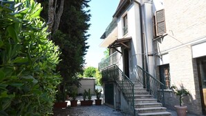 Ein Innenhof mit einer Treppe, die zu einem Gebäude führt, umgeben von Blumentöpfen.
