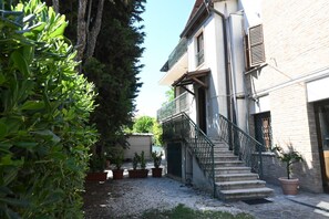 Un cortile con una scala che conduce a un edificio, circondato da piante in vaso.