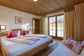 Ein Doppelbett mit Kissen, ein hölzernes Kopfende, ein Fenster mit Vorhängen und ein gerahmtes Bild an der Wand.