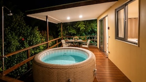 Un jacuzzi en una terraza de madera con una puerta de vidrio que da a una habitación.