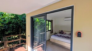 A room with a bed, a window with curtains, and a wooden deck outside.