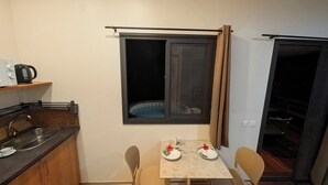 A compact kitchen with a sink, a kettle, and a small dining table with chairs.
