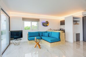 A modern living room with a sectional sofa, a glass coffee table, and a wall-mounted clock. - Private Suite with Panoramic Athens View (Athina)