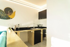 A modern kitchen with a black countertop, a stainless steel kettle, and a black cabinet above the sink. - Private Suite with Panoramic Athens View (Athina)