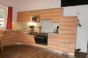 Eine moderne Küche mit Holzschränken, einer Mikrowelle, einem Backofen und einem Spülbecken.