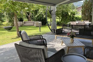 Eine Terrassenanlage im Freien mit Korbmöbeln, einem Tisch und einer überdachten Sitzgelegenheit.