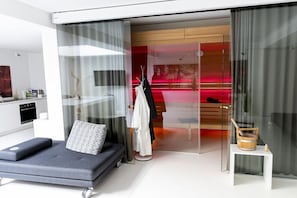 Ein modernes Zimmer mit einer Couch, einem kleinen Tisch und einer Glaskabine.