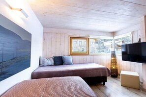 Ein Zimmer mit zwei Betten, einem Fernseher, einem Gemälde und einem Fenster mit Blick.
