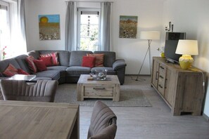 Ein Wohnzimmer mit einer Couch, einem Couchtisch, einem Fernseher und einem Holzschrank.