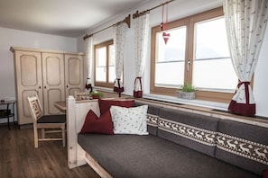 Ein gemütliches Zimmer mit einem Holzespeisetisch, einer gepolsterten Bank und einem Fenster mit Vorhängen.