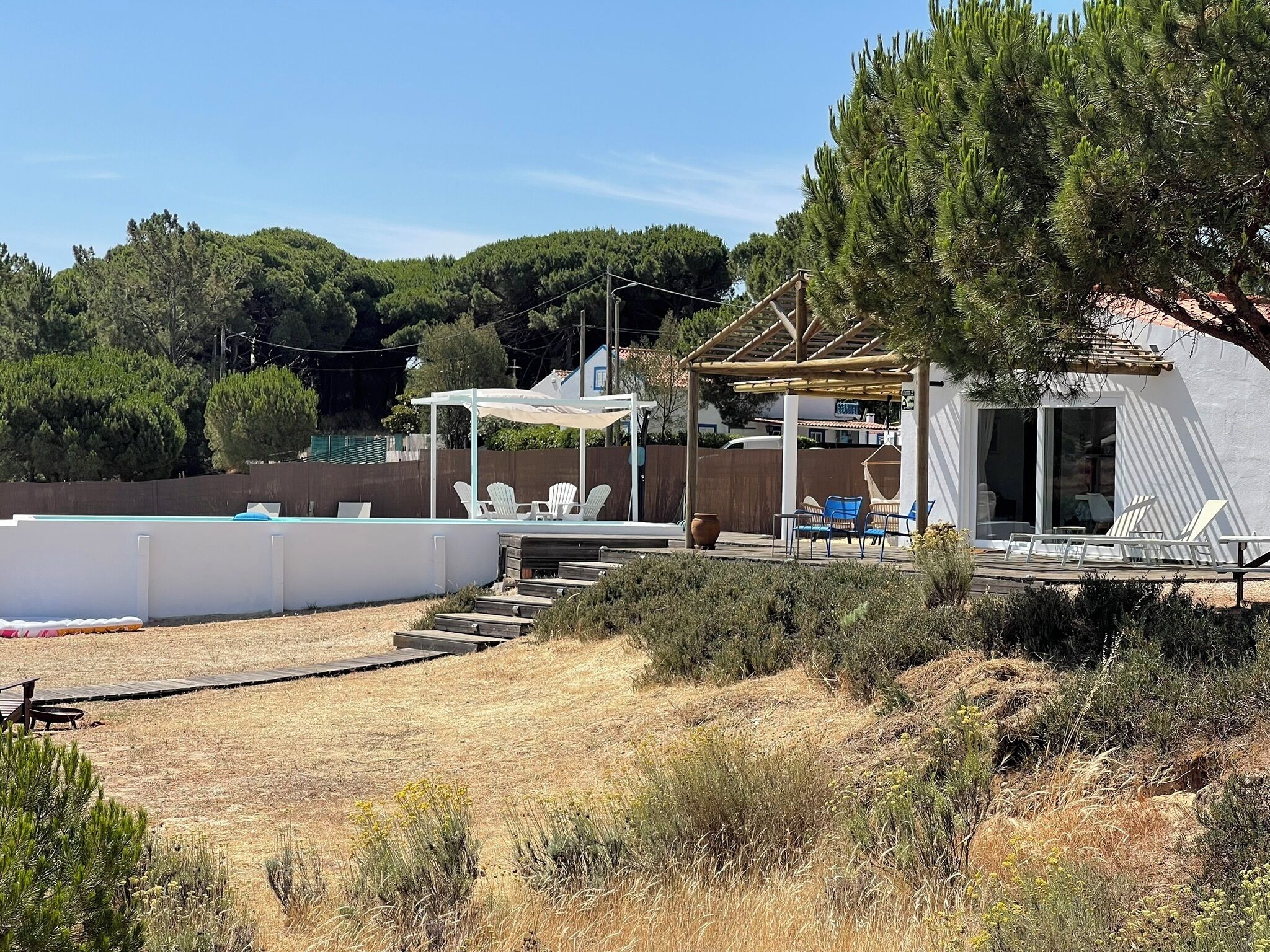 Un jardin avec une piscine, un espace salon extérieur et une pergola.