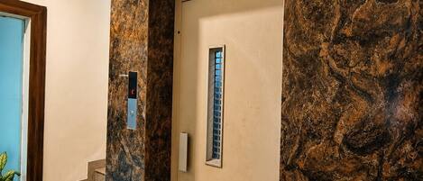 A modern interior with a marble wall, a staircase, and a door with a window.