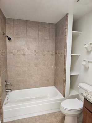Ein Badezimmer mit Badewanne, Toilette und Duschbereich.