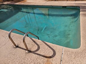 Ein klarer Pool mit einer Metallleiter zum hineinsteigen.
