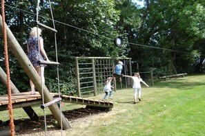 Ein Spielplatz mit Holzkonstruktionen, Seilen und einem Netzbereich.