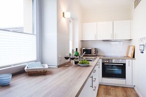 Eine moderne Küche mit weißen Schränken, einem eingebauten Backofen und einer Mikrowelle.