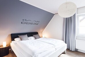 Ein modernes Schlafzimmer mit Bett, Nachttischen, einer Wandleuchte und einem Fenster mit Vorhängen.