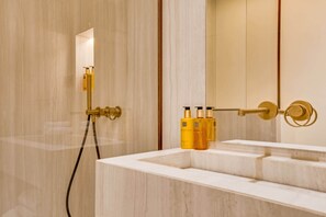 Ein Badezimmer mit Marmorwaschtisch, goldenen Armaturen und Pflegeprodukten.