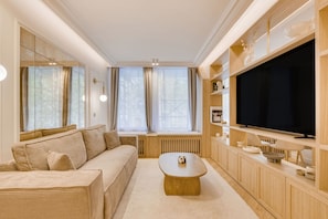 A modern living room with a sofa, coffee table, TV, and built-in shelving. - A Wonderfull 1-BR/2BA - Champs Elysées (Paris)