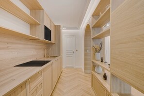Eine schmale Küche mit Holzschränken, einer schwarzen Arbeitsplatte und einer eingebauten Mikrowelle.