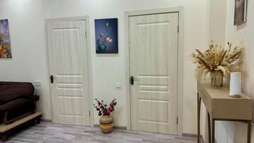 Une pièce avec deux portes fermées, un canapé marron, une petite table avec un vase et un tableau accroché au mur.