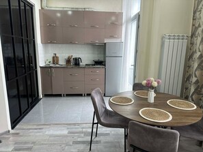 A modern kitchen with cabinets, a refrigerator, and a dining area with a table and chairs.