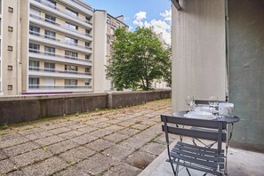 Ein Innenhof mit einem Tisch für zwei Personen, einer Bank und einem Baum.