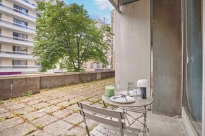 Ein Balkon mit einem Tisch für zwei Personen, einer grünen Kerze und einem Glas Wasser.