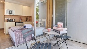 Ein gemütliches Schlafzimmer mit Bett, Nachttisch und einem kleinen Balkon mit Tisch und Stühlen.