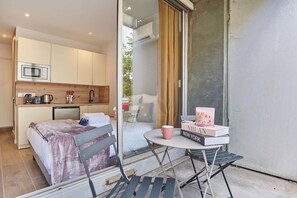 Ein gemütliches Schlafzimmer mit Bett, Nachttisch und einem kleinen Balkon mit Tisch und Stühlen.