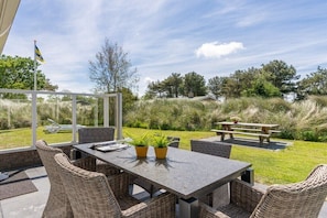 Eine Terrasse im Freien mit Korbmöbeln, einem Tisch und Blumentöpfen.