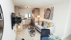A modern living room with a sofa, a coffee table, and a TV mounted on the wall. - Queensferry Collection - Residence 5 (Derby)
