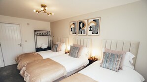 A hotel room with two beds, a wardrobe, a hanging rack, and wall art. - Queensferry Collection - Residence 5 (Derby)