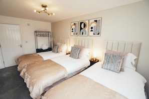 A hotel room with two beds, a wardrobe, a hanging rack, and wall art. - Queensferry Collection - Residence 5 (Derby)