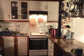 A kitchen with wooden cabinets, a stove, a sink, and various kitchen utensils. - Holiday apartment with 3 bedrooms (Karlsborg)