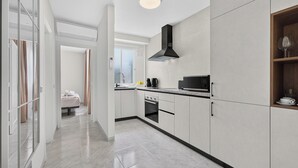 Una cocina moderna con armarios blancos, una campana extractora negra y una ventana con vistas a un paisaje urbano.