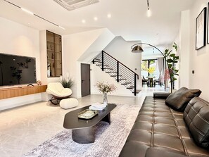 Ein modernes Wohnzimmer mit einer Couch, einem Couchtisch, einem Fernseher und einer Treppe zu einem anderen Raum.