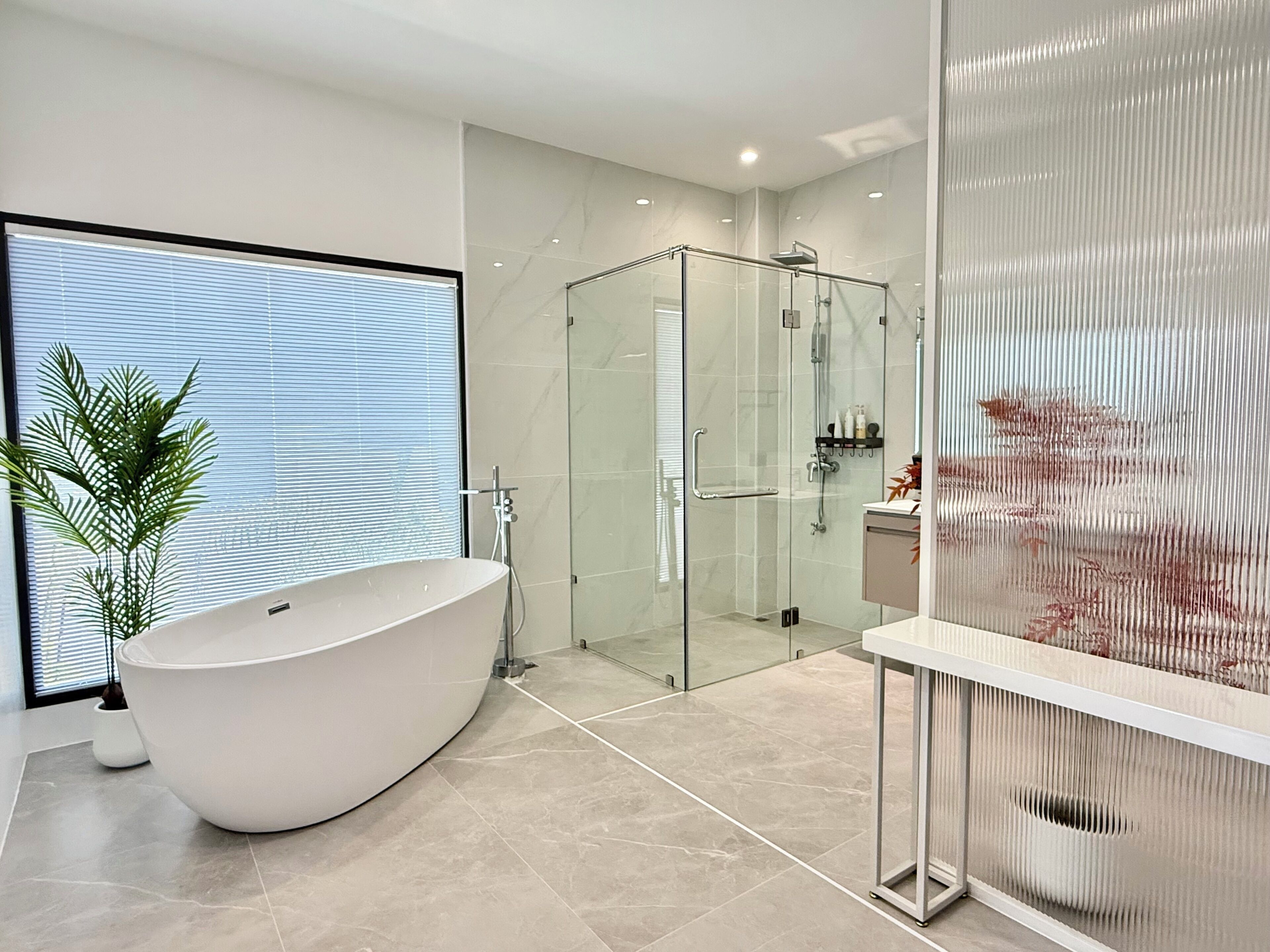 Une salle de bain moderne avec une baignoire sur pieds, une douche à parois de verre et une grande fenêtre équipée de stores.