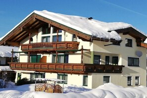 Ein mehrstöckiges Gebäude mit Holzbalkon und schneebedecktem Dach.