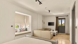 A modern hotel room with a bed, a sofa, a small table, a TV, and a window with curtains. - Molino Hotel (Çeşme)