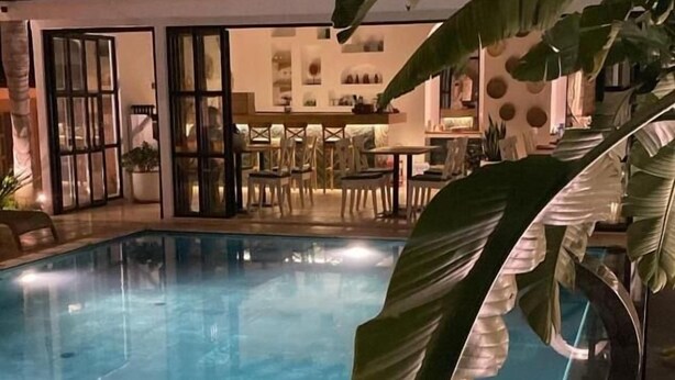 A swimming pool with a glass enclosure, surrounded by tropical plants and a dining area with chairs and tables. - Molino Hotel (Çeşme)
